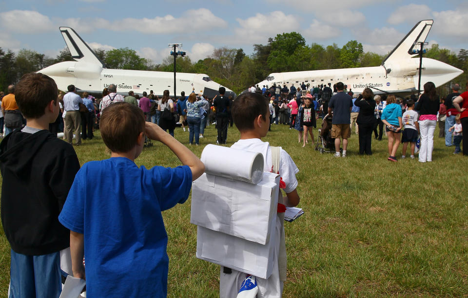 Young boys watch as the Space Shuttle Discovery (R), and the Space Shuttle Enterprise (L), sit nose to nose, during an event at the Smithsonian National Air and Space Museum Steven F. Udvar-Hazy Center April 19, 2012 in Chantilly, Virginia. The space shuttle Discovery is the he oldest and most traveled vehicle from NASA's space shuttle program, and will replace the Interprise at the museum. (Photo by Mark Wilson/Getty Images)