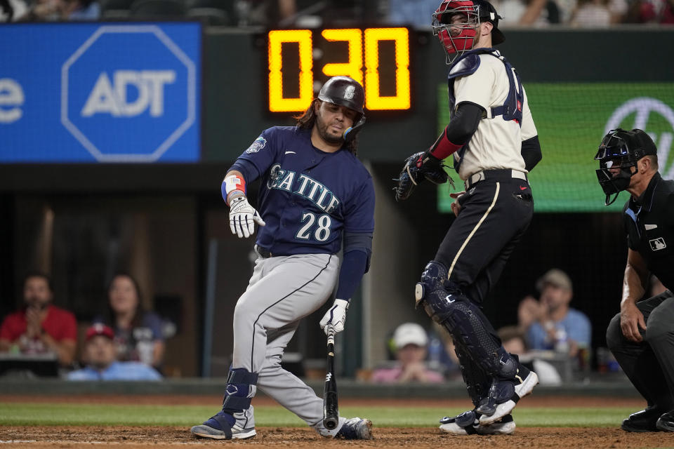 Seattle Mariners' Eugenio Suarez (28) strikes out swinging as Texas Rangers catcher Jonah Heim (28) and umpire Jim Wolf, right, look on in the ninth inning of a baseball game, Saturday, Sept. 23, 2023, in Arlington, Texas. (AP Photo/Tony Gutierrez)