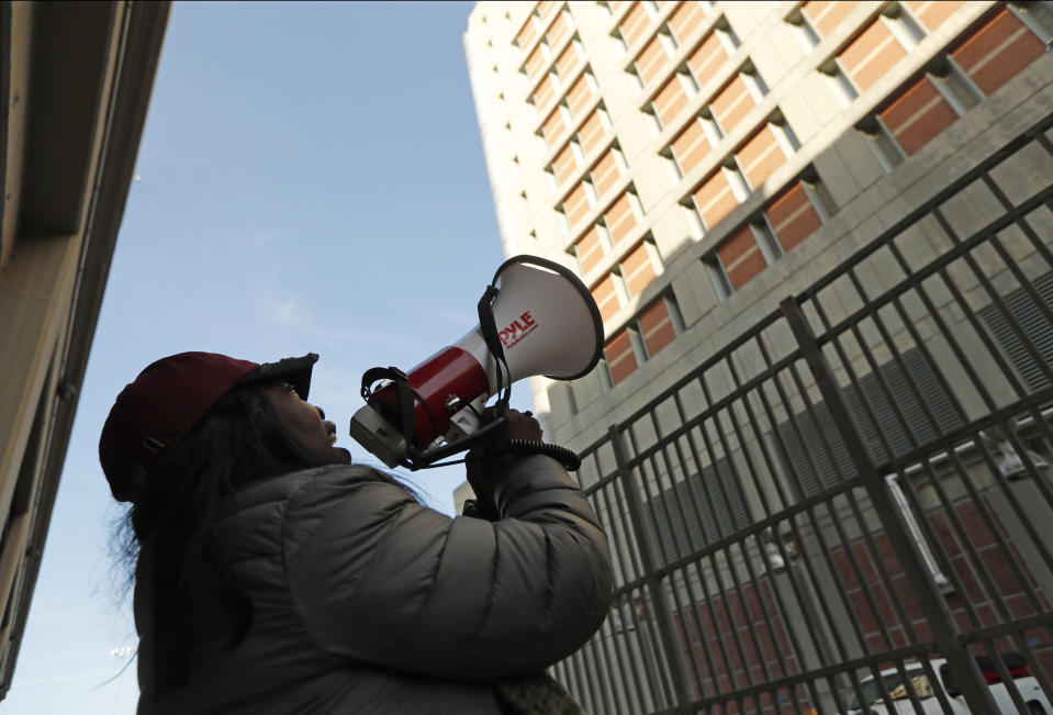 Catana Yehudah, of the Bronx, uses a megaphone to speak to prisoners from outside the Metropolitan Detention Center, a federal prison of all security levels, where prisoners haven't had access to heat, hot water, electricity and sanitary conditions since earlier in the week, including through the recent frigid weather, Sunday, Feb. 3, 2019, in the Brooklyn borough of New York. Yehudah has a brother who is serving an 18-month sentence for gun possession. (AP Photo/Kathy Willens)