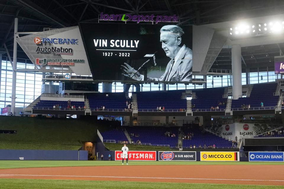 Fans and players stand for a moment of silence in honor of Vin Scully before the start of a baseball game between the Miami Marlins and the Cincinnati Reds, Wednesday, Aug. 3, 2022, in Miami. The legendary Dodgers broadcaster died at 94.