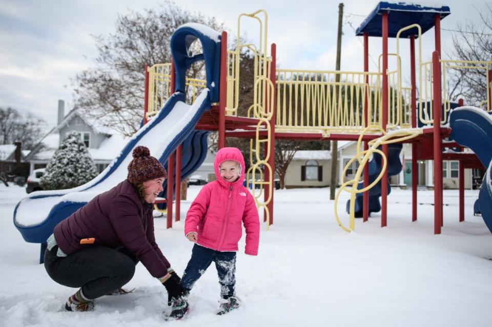 Hallie Bartlett, left, works on putting her daughter Claire's show back on while playing in the snow at General Lee Park in Fayetteville on Saturday, Jan. 22, 2022.