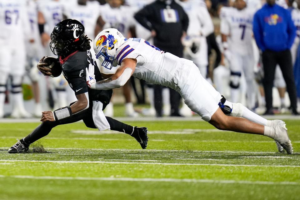 Cincinnati quarterback Emory Jones (5) looks to make a play as Kansas defensive lineman Austin Booker (9) tackles him to the ground during a college football game on Nov. 25, 2023 at Nippert Stadium in Cincinnati.