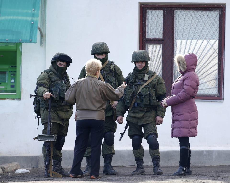 Local residents speak with armed men, believed to be Russian servicemen, outside a Ukrainian military base in the village of Perevalnoye outside Simferopo
