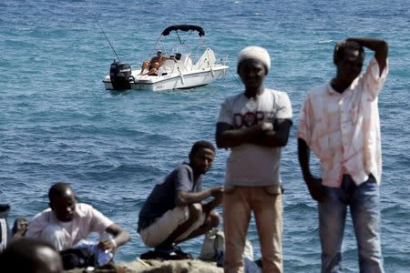 A man fishes from his boat as a group of migrants gather on the seawall at the Saint Ludovic border crossing on the Mediterranean Sea between Vintimille, Italy and Menton, France, in this June 14, 2015 file photo. REUTERS/Eric Gaillard/Files