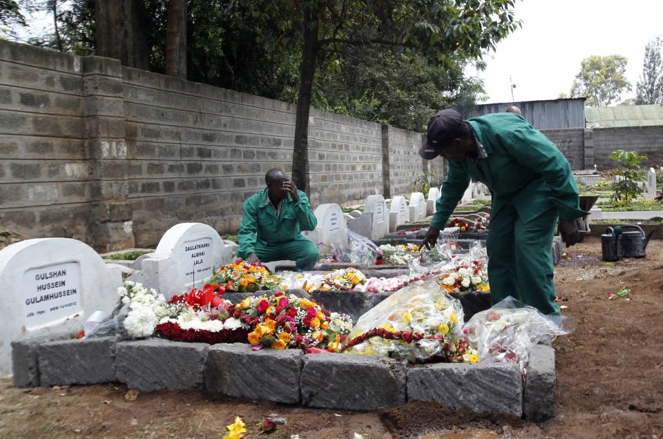 Cemetery workers arrange flowers on the grave of Kenyan journalist Ruhila Adatia Sood, who was killed in the Westgate shopping mall attack, during her funeral in Nairobi