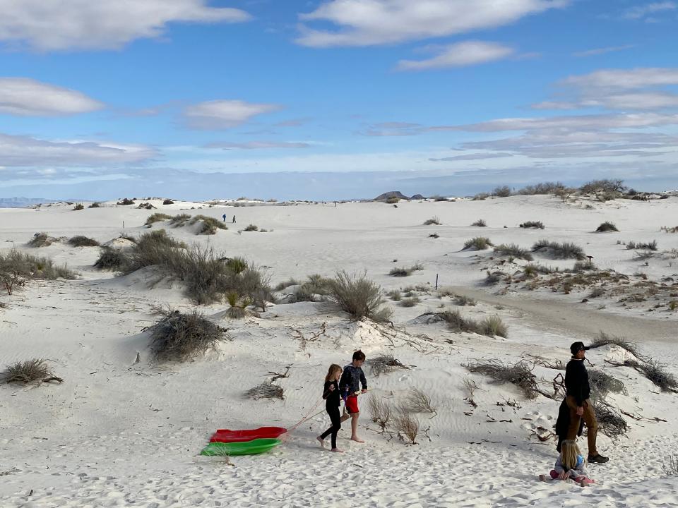 A family takes sleds to White Sands National Park for sliding down snow-white dunes. Sledding and hiking are favorite activities in the national park near Alamogordo, New Mexico.