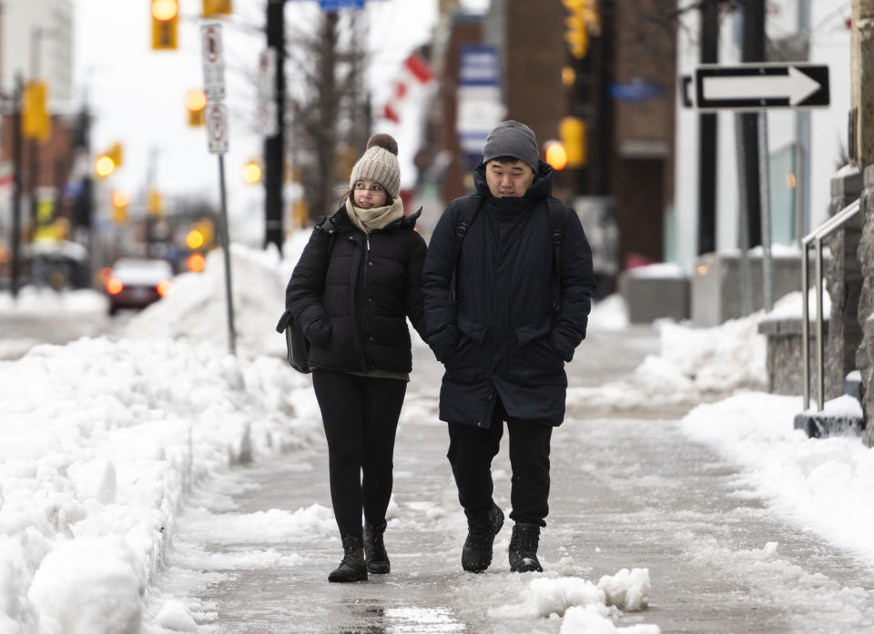 Pedestrians make their way along Ottawa's Elgin Street amid high winds, as a winter storm warning is in effect, on Friday, Dec. 23, 2022. (Justin Tang /The Canadian Press via AP)