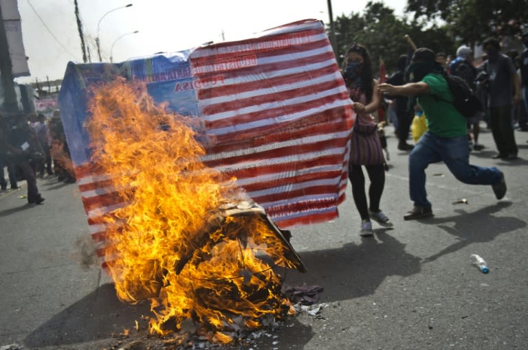 Demonstrators burn a US flag during a protest against the IMF/World Bank annual meetings taking place in Lima, Peru on October 9, 2015