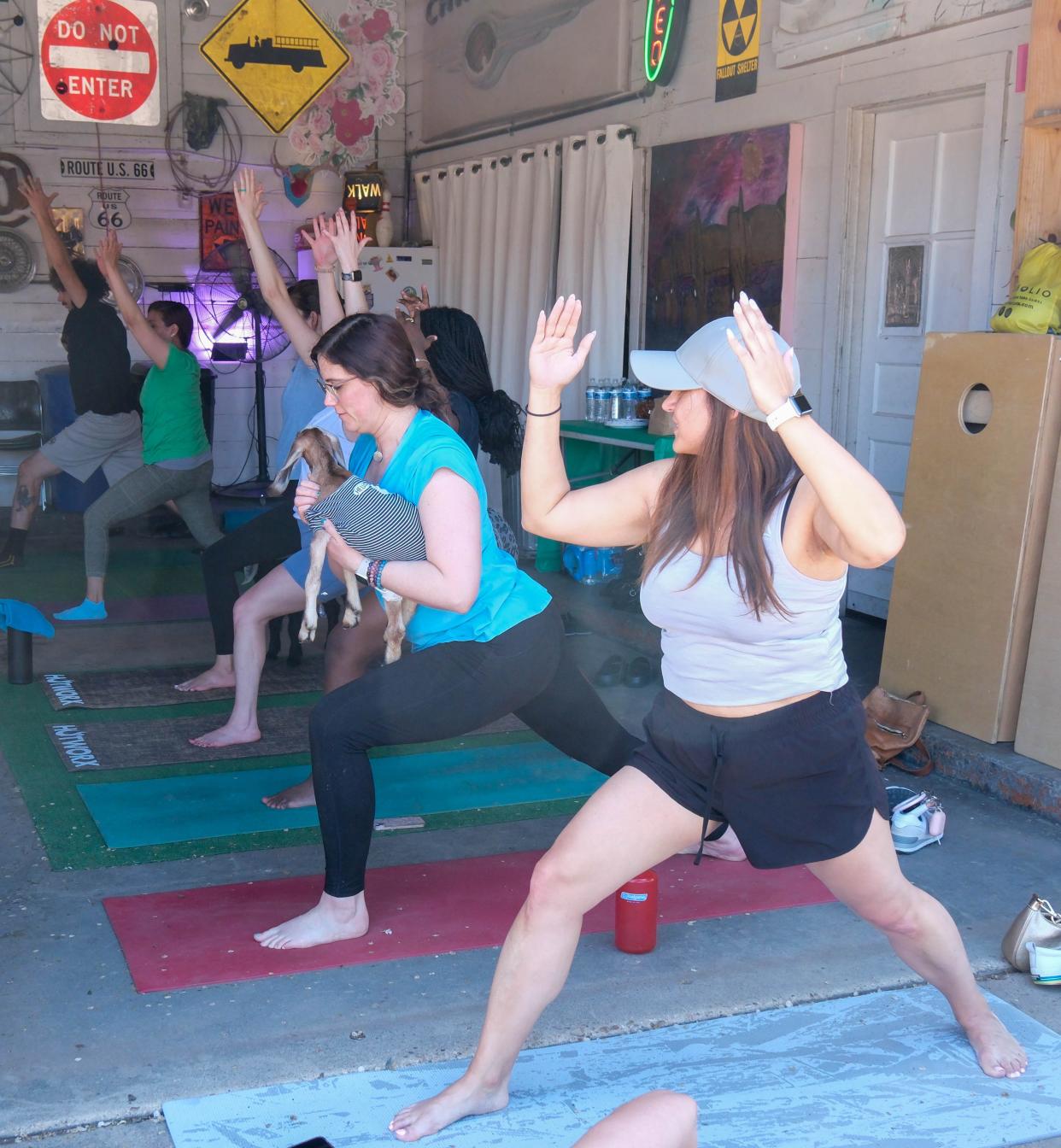 A young woman holds a goat as she does a yoga pose during goat yoga last weekend at The Garage event venue on the Historic Route 66 in Amarillo.