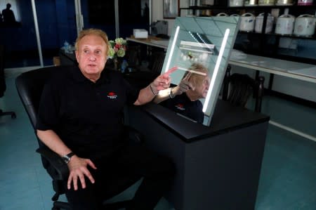 Larry Sloven shows a touch mirror that can be used as a tablet, at a factory in Bangkok