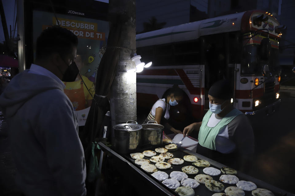 Gertrudis Hernandez sells "pupusas" at a bus stop in San Salvador, El Salvador, before sunrise Tuesday, Sept. 7, 2021, on the day all businesses have to accept payments in Bitcoin, except those lacking the technology to do so. Hernandez said she'll learn how to use Bitcoin when needed, just like the dollar. (AP Photo/Salvador Melendez)