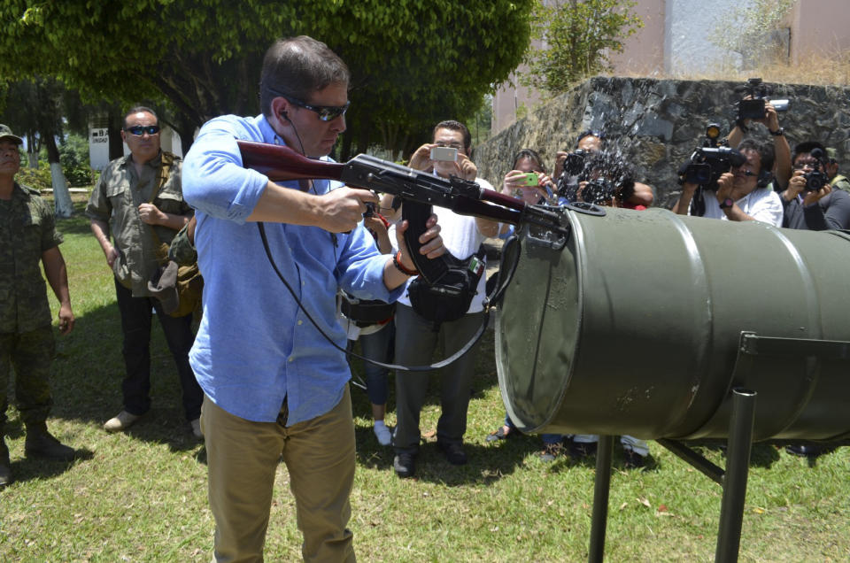 The federal envoy to the embattled state of Michoacan, Alfredo Castillo, fires a weapon into a water filled barrel on the first day of weapons registration in Coalcoman, Mexico, Monday, 28, 2014. The confusing proliferation of false self-defense groups in Michoacan and instances of alleged looting and killings by legitimate vigilantes have led the federal government to tell the vigilantes they have to demobilize by May 10 but the vigilantes, who usually carry assault rifles that are prohibited for civilian use, only have to turn in their heaviest weapons, such as .50-caliber sniper rifles. They will be allowed to keep, but not publicly carry, AR-15 and AK-47 assault rifles, as long as they register them with the army. (AP Photo/Agencia Esquema)