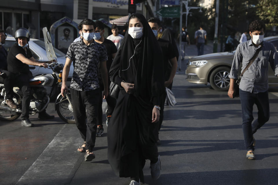 People wearing protective face masks to help prevent the spread of the coronavirus cross an intersection in downtown Tehran, Iran, Sunday, Sept. 20, 2020. Iran's president dismissed U.S. efforts to restore all U.N. sanctions on the country as mounting economic pressure from Washington pushed the local currency down to its lowest level ever on Sunday. (AP Photo/Vahid Salemi)