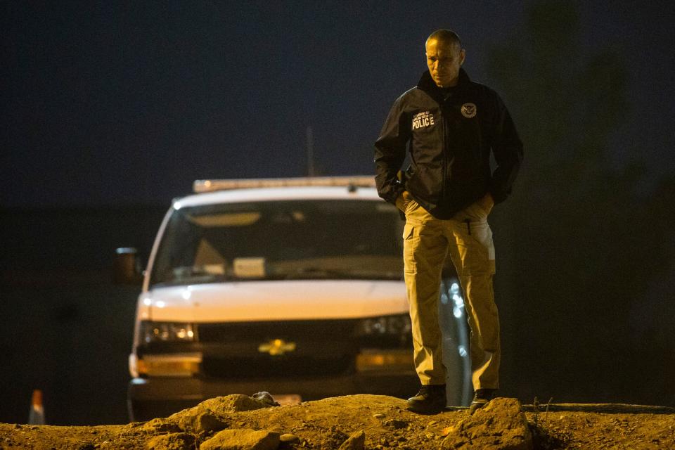 A U.S. Department of Homeland Security officer observes migrants on the bank of the Rio Grande as hundreds of migrants crossed hoping to seek asylum last December in El Paso.