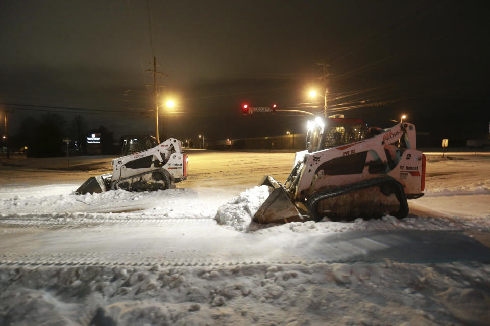 Crews with Tupelo Public Works begin to clear the intersection of South Green and Eason Blvd., Monday night, Feb. 15, 2021, as they work through the night to make the roads safe for travel in Tupelo, Miss. (Thomas Wells/The Northeast Mississippi Daily Journal via AP)