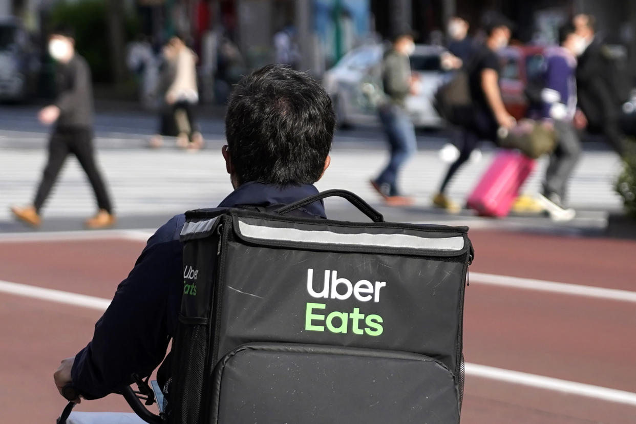 FILE - In this April 28, 2021, file photo, an Uber Eats delivery person rides a bicycle through the Shinjuku district in Tokyo, Japan. 