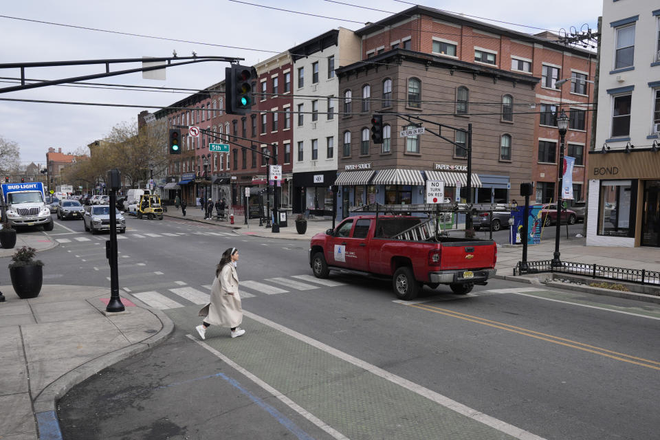 Pedestrians cross the street at the intersection of Washington and 5th in Hoboken, N.J., Thursday, Feb. 22, 2024. This intersection has curb extenders, bottom left, which bumps out the sidewalk near crosswalks, preventing parking near the intersection and increasing visibility for pedestrians. (AP Photo/Seth Wenig)