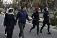 Two women jog with face masks on as others walk while enjoying their weekend afternoon at Pardisan Park in Tehran, Iran, Friday, Feb. 28, 2020. Iranians in Tehran on Friday found time to enjoy their weekend, even as authorities canceled Friday prayers and closed universities, schools and parliament over fears about the new coronavirus. (AP Photo/Vahid Salemi)