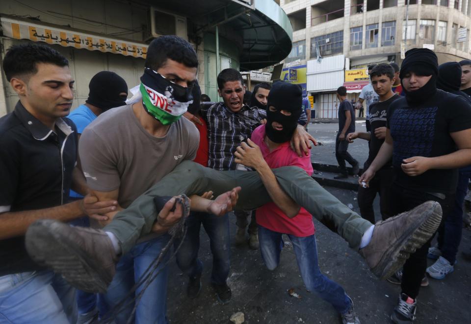 Palestinians carry injured protester during clashes with Israeli security forces in Hebron