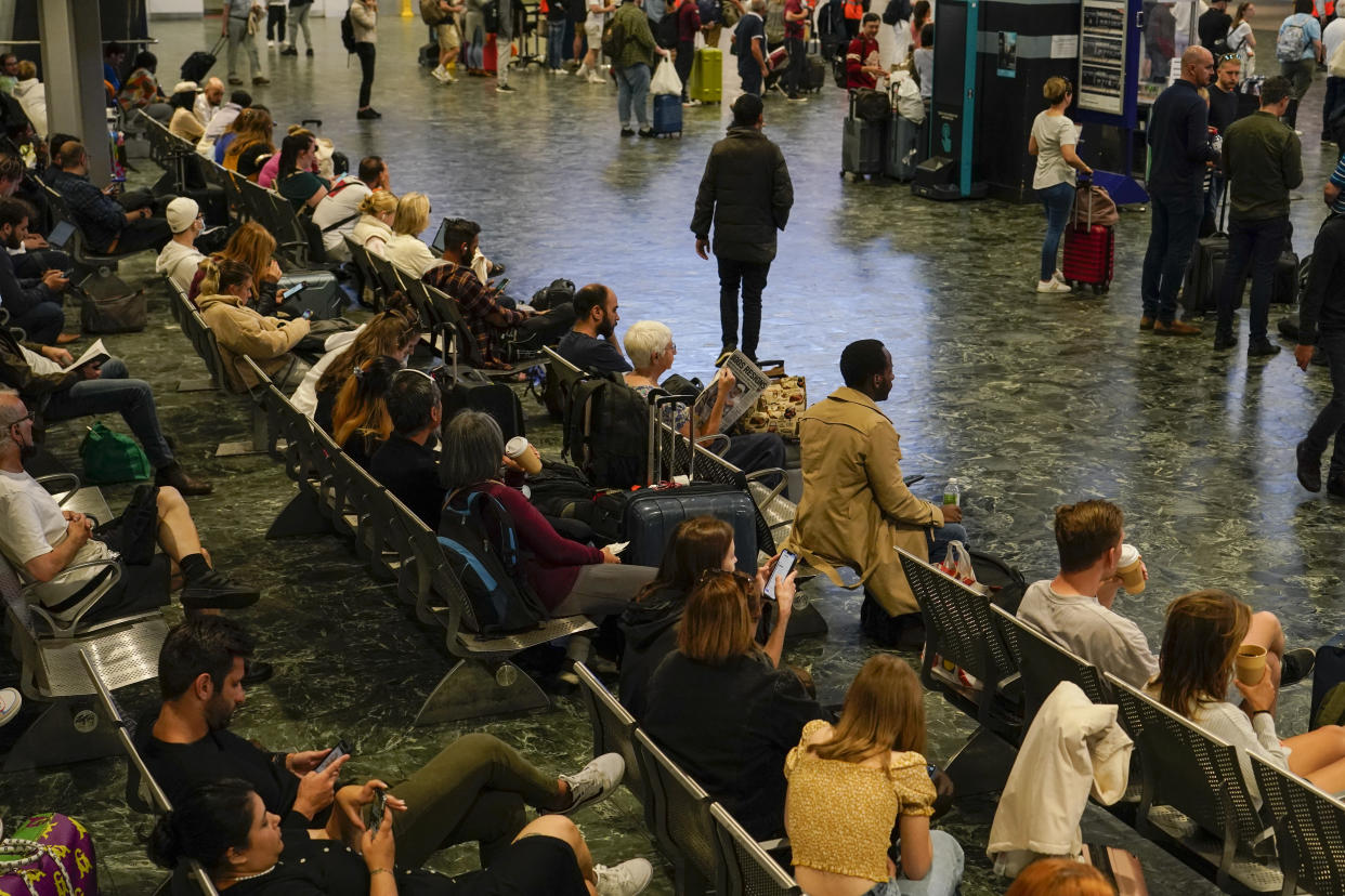 Passengers sit as they await their trains to be announced, at a quiet Euston station, in London, Tuesday, June 21, 2022. Tens of thousands of railway workers walked off the job in Britain on Tuesday, bringing the train network to a crawl in the country’s biggest transit strike for three decades. (AP Photo/Alberto Pezzali)