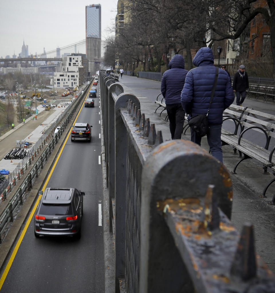 Visitors walk along Brooklyn Heights Promenade while traffic travels beneath the park, Friday April 5, 2019, in New York. The promenade makes up the top deck overhang of a deteriorating Brooklyn-Queens Expressway and the city's plans for repairs has drawn neighborhood protest, since it calls for a temporary six lane highway on the promenade. (AP Photo/Bebeto Matthews)