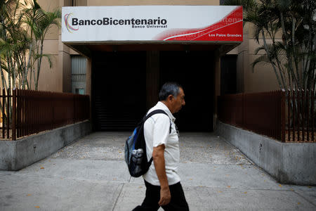 A man walks past a branch of Banco de Bicentenario in Caracas, Venezuela March 22, 2019. REUTERS/Carlos Garcia Rawlins