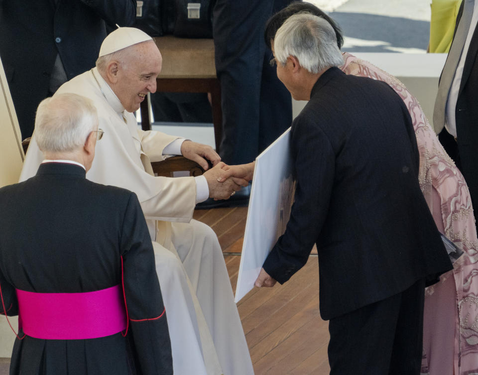Pulitzer Prize-winning photographer Nick Ut, center, and UNESCO Ambassador Kim Phuc, right, show to Pope Francis Ut's 1973 Pulitzer winning photo of Kim Phuc fleeing her village that was accidentally hit by napalm bombs dropped by the South Vietnamese air force, at the end of a general audience in St. Peter's Square at The Vatican, Wednesday, May 11, 2022. Ut and Phuc are in Italy to promote the photo exhibition "From Hell to Hollywood" resuming Ut's 51 years of work at the Associated Press. (AP Photo/Domenico Stinellis)