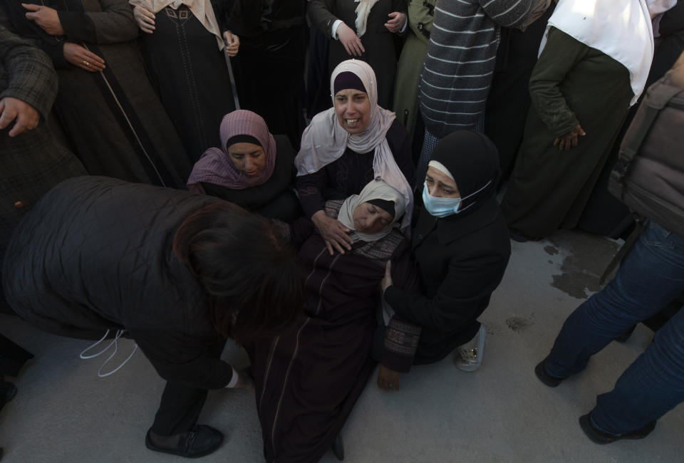 Palestinian women help a fellow mourner who has fainted after taking the farewell look at the body of Atef Hanaisheh, 45 during his funeral procession in the West Bank village of Beit Dajan, east of Nablus, Friday, March 19, 2021. The Palestinian Health Ministry said Israeli troops shot and killed a Palestinian protester during clashes in the occupied West Bank. (AP Photo/Nasser Nasser)