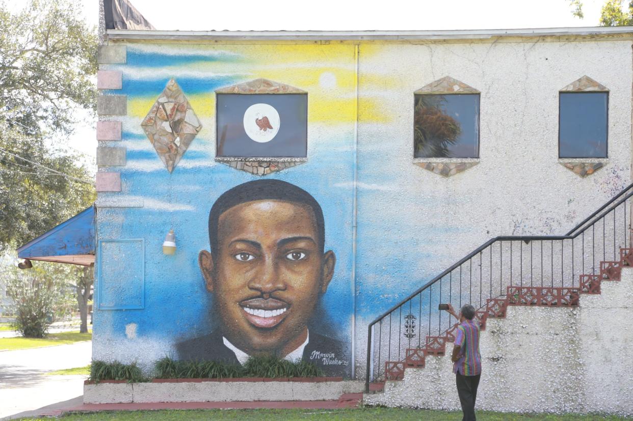 A man uses his phone to record the Ahmaud Arbery mural on the side of the Brunswick African American Cultural Center.