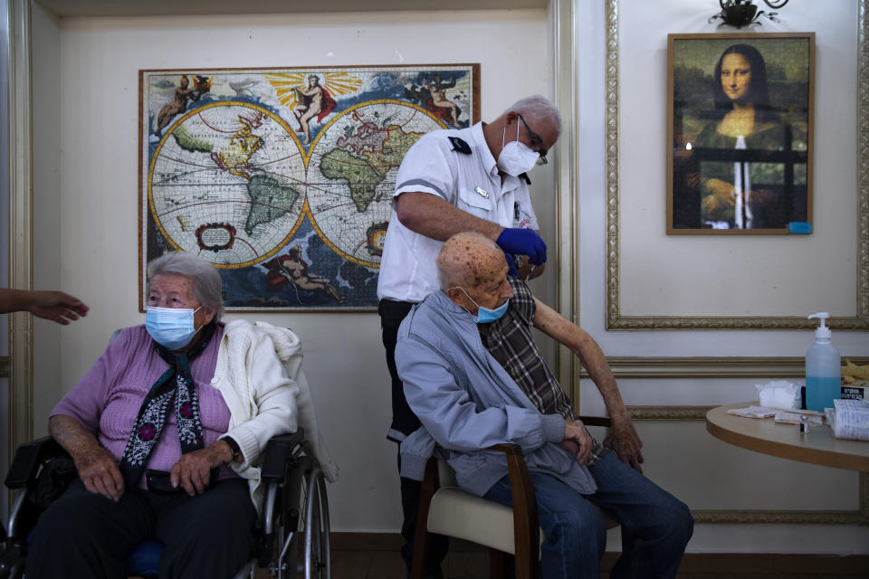 FILE - In this Jan. 13, 2021 file photo, a man receives his second Pfizer-BioNTech COVID-19 vaccine from a Magen David Adom national emergency service volunteer, at a private nursing home, in Ramat Gan, Israel, during a nationwide lockdown to curb the spread of the virus. More than a month into its coronavirus vaccination drive, as inoculation rates are flagging, Israel is employing carrots and sticks to combat misinformation about the COVID-19 vaccine and encourage its citizens to go get immunized. (AP Photo/Oded Balilty, File)