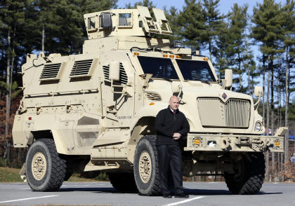 Warren County Undersheriff Shawn Lamouree poses in front the department's mine resistant ambush protected vehicle, or MRAP, on Wednesday, Nov. 13, 2013, in Queensbury, N.Y. The hulking vehicles, built for about $500,000 each at the height of the war, are among the biggest pieces of equipment that the Defense Department is giving to law enforcement agencies under a national military surplus program. (AP Photo/Mike Groll)