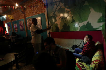 Venezuelan migrant Enrique Miller, 44, takes a picture of customers at a restaurant where mainly migrants work, at the Chilean and Peruvian border in Arica, Chile, November 16, 2018. REUTERS/Ivan Alvarado