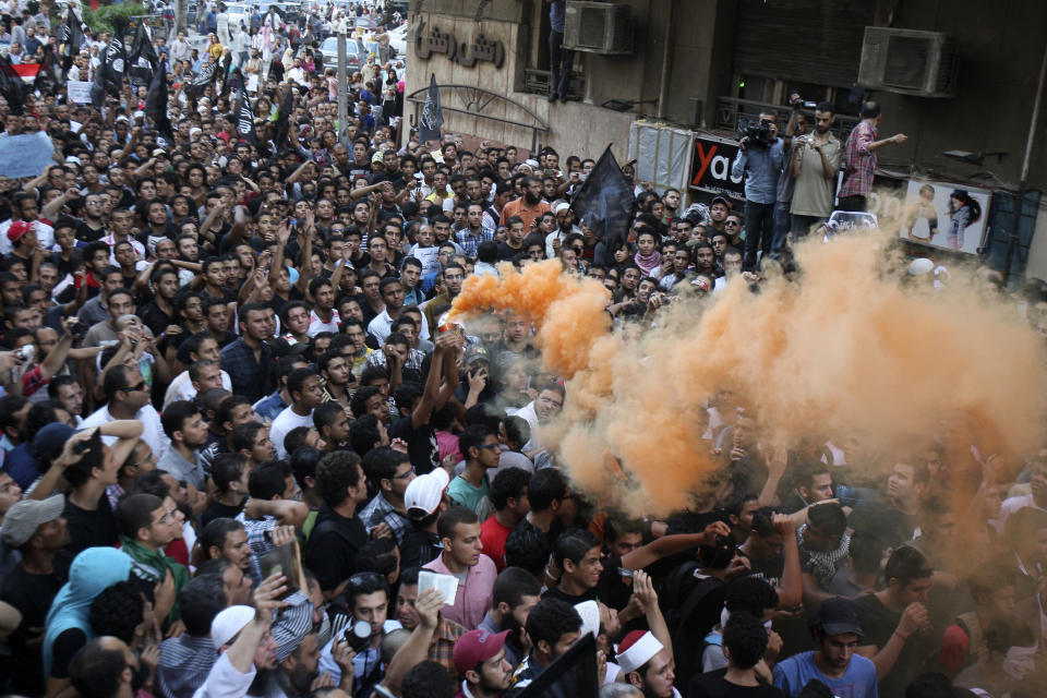 Protesters chant slogans amid orange smoke outside the U.S. embassy in Cairo, Egypt, Tuesday, Sept. 11, 2012. Egyptian protesters, largely ultra conservative Islamists, have climbed the walls of the U.S. embassy in Cairo, went into the courtyard and brought down the flag, replacing it with a black flag with Islamic inscription, in protest of a film deemed offensive of Islam. (AP Photo/Mohammed Abu Zaid)