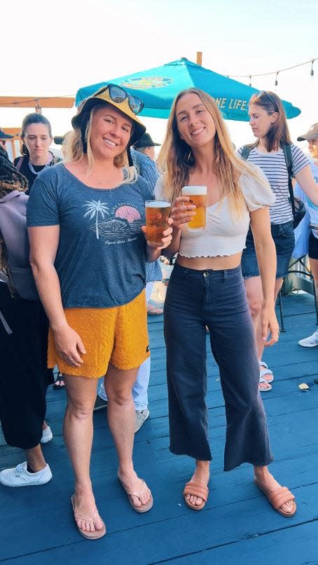 Surf photographer Sarah Lee (left) and professional surfer Anna Gudauskas, enjoy a couple cold Kona beers following their beach cleanup in Rockaway Beach, N.Y.