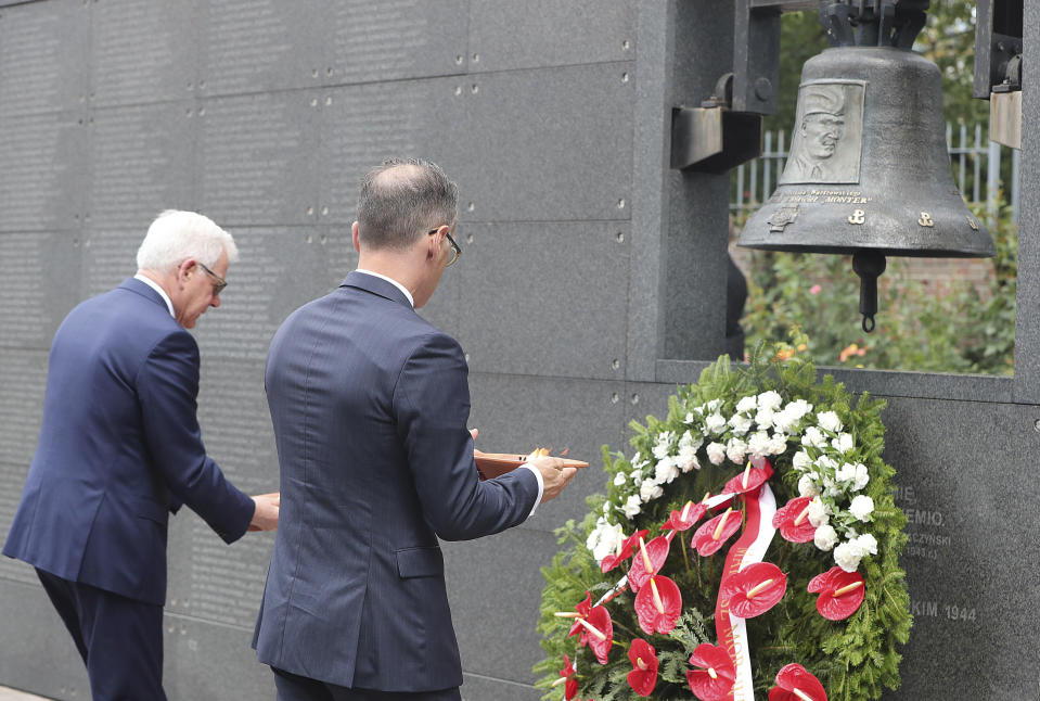 Polish Foreign Minister Jacek Czaputowicz, left, and his German counterpart Heiko Maas, right, pay homage to the victims of the Warsaw Uprising, a failed revolt by Poles against the occupying Nazi German forces, in Warsaw, Poland, Thursday, Aug. 1, 2019 on the 75th anniversary of the start of the two-month battle. (AP Photo/Czarek Sokolowski)