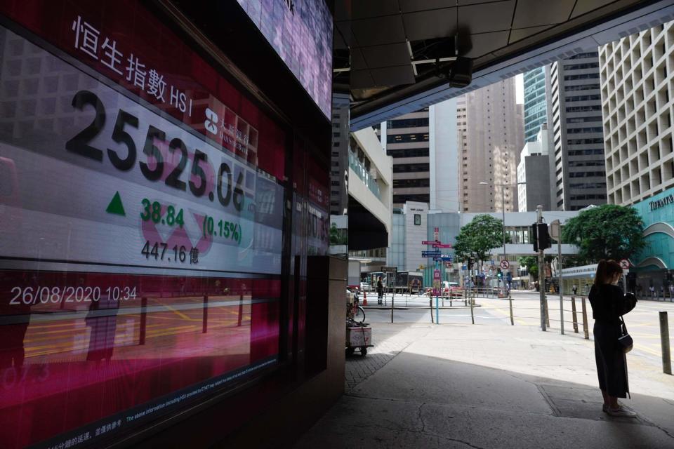 A woman walks past a bank electronic board showing the Hong Kong share index outside a local bank in Hong Kong, Wednesday, Aug. 26, 2020. Asian shares were mostly lower Wednesday after a lackluster session on Wall Street following talks between the United States and China on the status of a deal meant to work as truce in their trade war.(AP Photo/Vincent Yu)