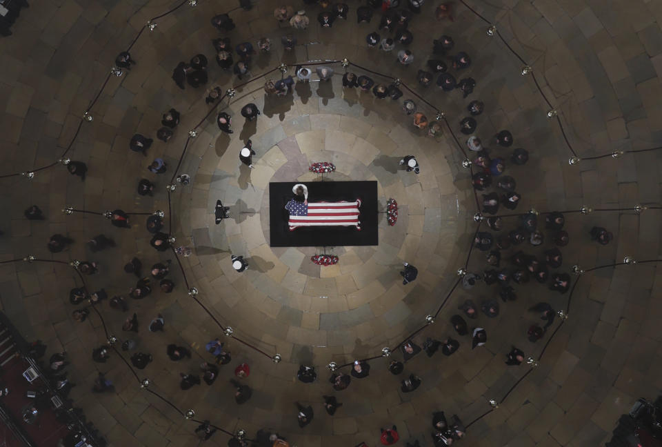 A mourner puts a hand on the flag-draped casket of former President George H. W. Bush as he lies in state in the U.S. Capitol Rotunda Tuesday, Dec. 4, 2018, in Washington. (Pool photo by Morry Gash via AP)