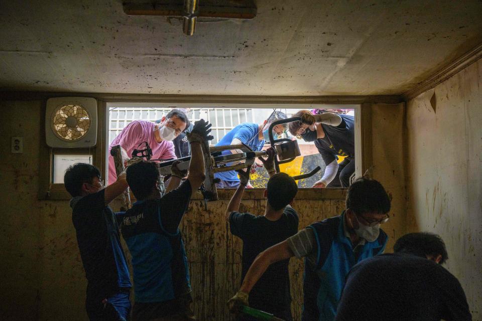 Workers clear debris from a waterlogged, mud-covered basement flat known as 