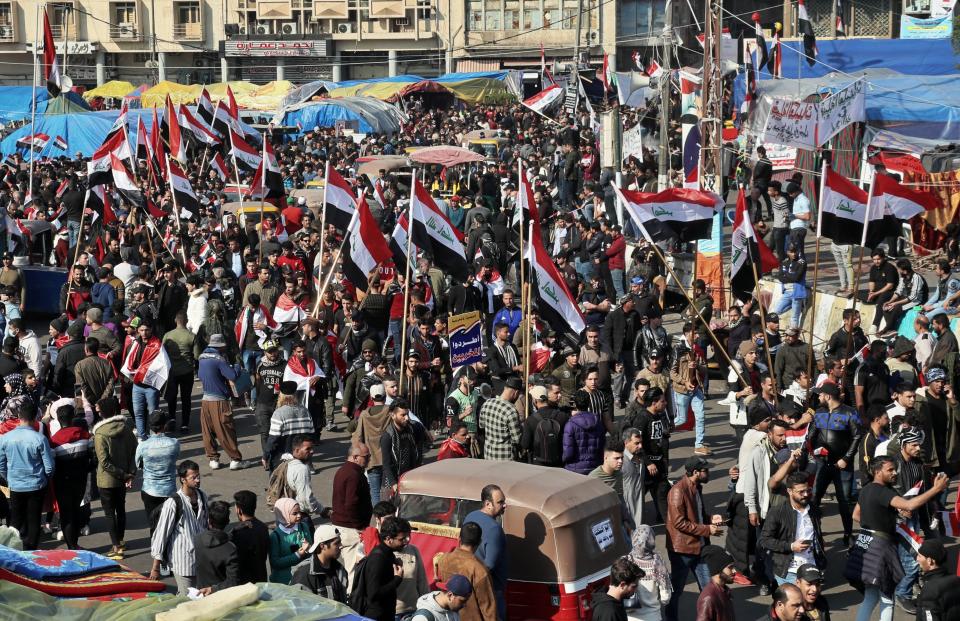 Hundreds of people march inside Tahrir Square carrying national flags and chanting religious slogans in Baghdad, Iraq, Thursday, Dec. 5, 2019. Anti-government protesters at least 15 people have suffered stab wounds in Baghdad's Tahrir Square, the epicenter of their movement, after political parties and Iran-backed militia groups briefly joined them, raising fears of infiltration by authorities. (AP Photo/Hadi Mizban)