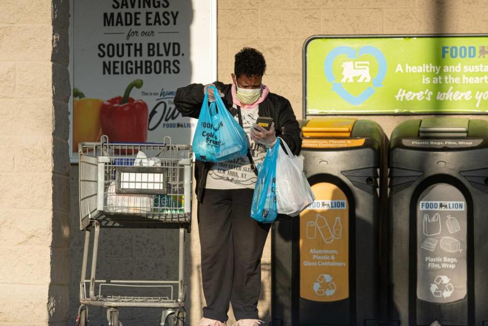 A woman outside of Food Lion on South Boulevard attempts to text with gloves on during the COVID-19 scare.