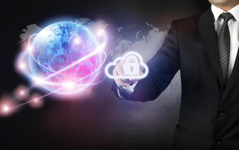 Businessman manipulating a computer icon of a cloud with a padlock, all in front of a world map and an energized globe.