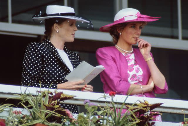 <p>British Royals Sarah, Duchess of York, wearing a dark blue outfit with white polka dots and white wide brim hat with a dark blue band, and Diana, Princess of Wales</p> Sarah Ferguson, the Duchess of York, and Princess Diana at the the Derby Day meeting at Epsom Downs Racecourse in June 1987.