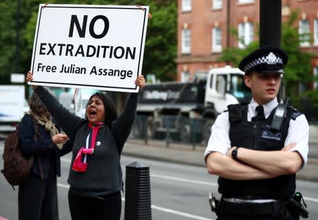 A demonstrator holding a placard protests as a police officer stands guard outside of Westminster Magistrates Court, where a case hearing for U.S. extradition of Wikileaks founder Julian Assange is held, in London
