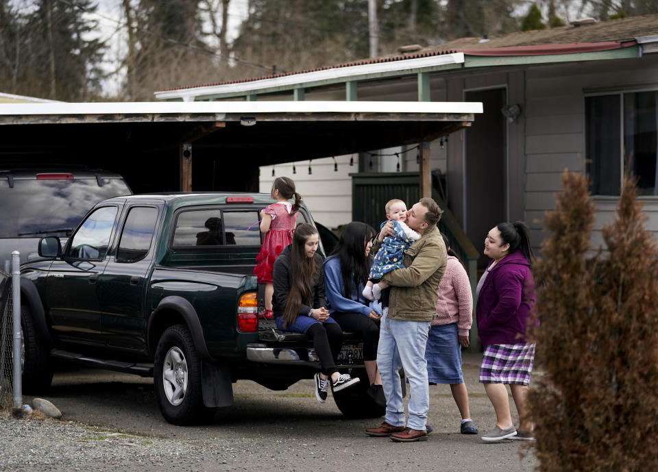 Gadiel Galvez, 22, kisses his son, 9-month-old Ezra, as he and family members gather outside his home in Bob’s and Jamestown Homeowners Cooperative, a resident-owned mobile home park in Lakewood, Wash., on Saturday, March 25, 2023. When residents learned the park’s owner was looking to sell, they formed a cooperative and bought it themselves amid worries it would be redeveloped. Since becoming owners in September 2022, residents have worked together to manage and maintain the park. (AP Photo/Lindsey Wasson)