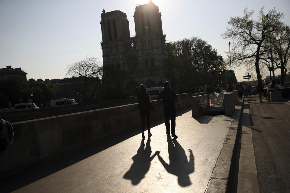 Two people walk by a the Notre Dame Cathedral in Paris, Saturday, April 20, 2019. Yellow vest protests are scheduled to take place in Paris and other regions of France over the weekend, with a heightened security presence anticipated. (AP Photo/Francisco Seco)