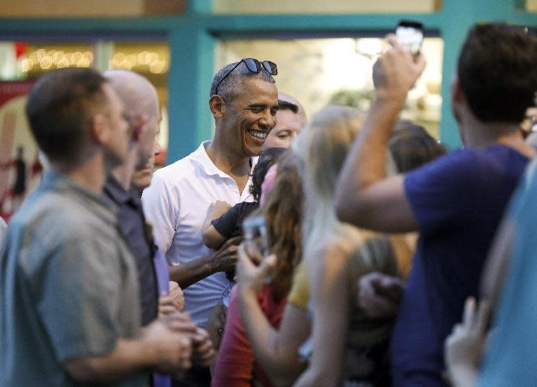 President Barack Obama greets people waiting for him outside Island Snow Hawaii in Kailua, Hawaii, Saturday, Dec. 24, 2016, after the president, joined by family and friends, had shave ice during the first family's annual vacation. (AP Photo/Carolyn Kaster)