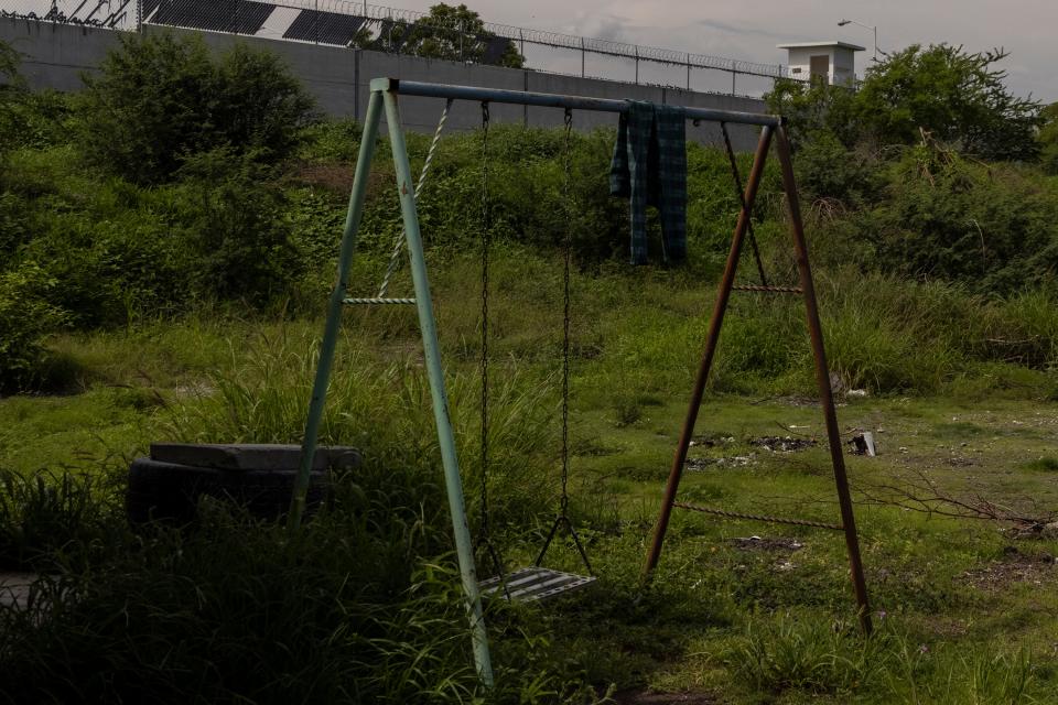 An abandoned swing set sits rusting outside the walls of a prison in Apatzingan, in Michoacán state, Mexico. August 2023.