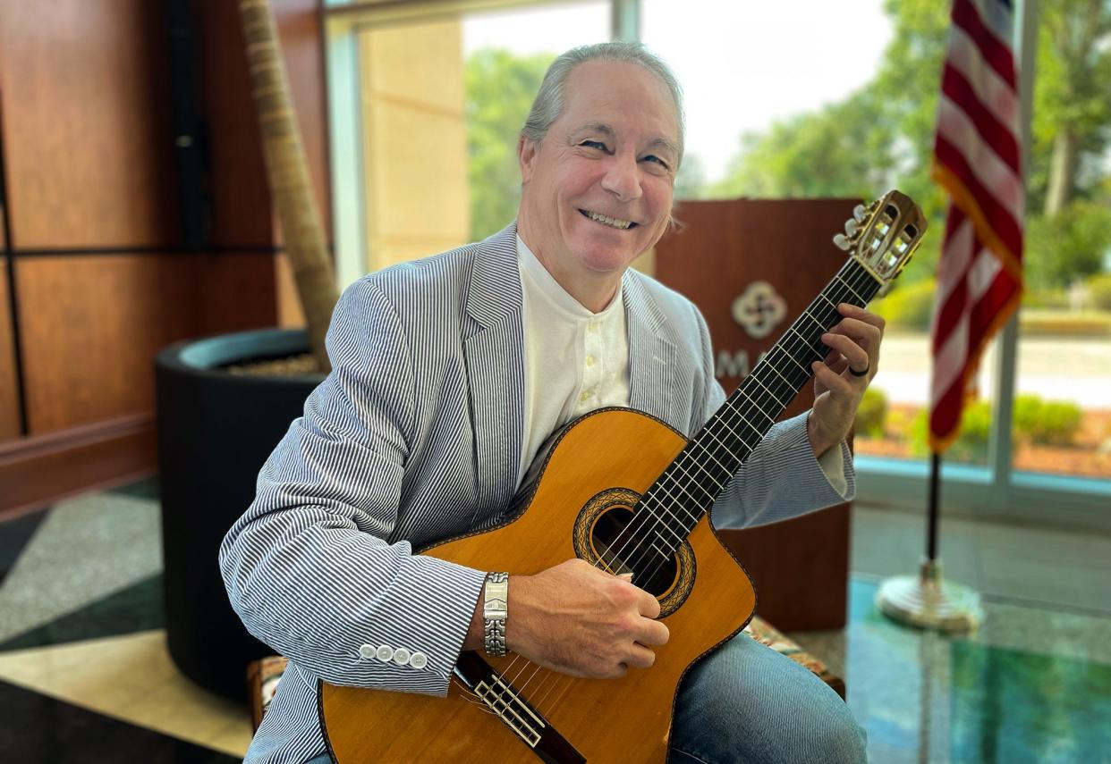 Athens musician Mark Maxwell poses with his guitar in the atrium at St. Mary's Hospital in Athens, Ga. on Tuesday, July 25, 2023. A lullaby that Maxwell composed and recorded in 1992 plays at the hospital every time a new baby is born.