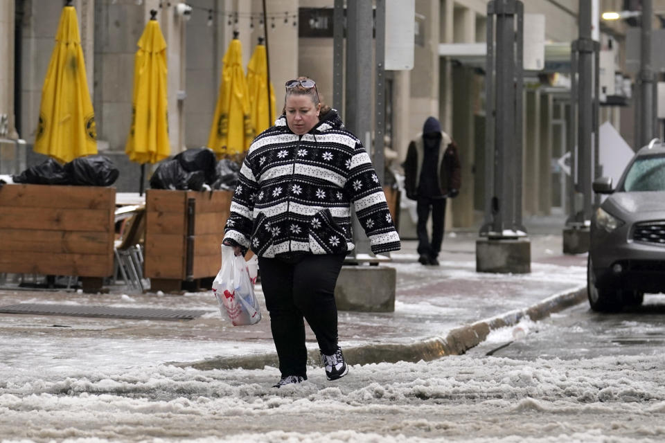 Jana Belden of Ogden, Utah, watches her steps as she crosses a busy intersection filled with ice and slush, Wednesday, Feb. 1, 2023, in downtown Dallas. (AP Photo/Tony Gutierrez)