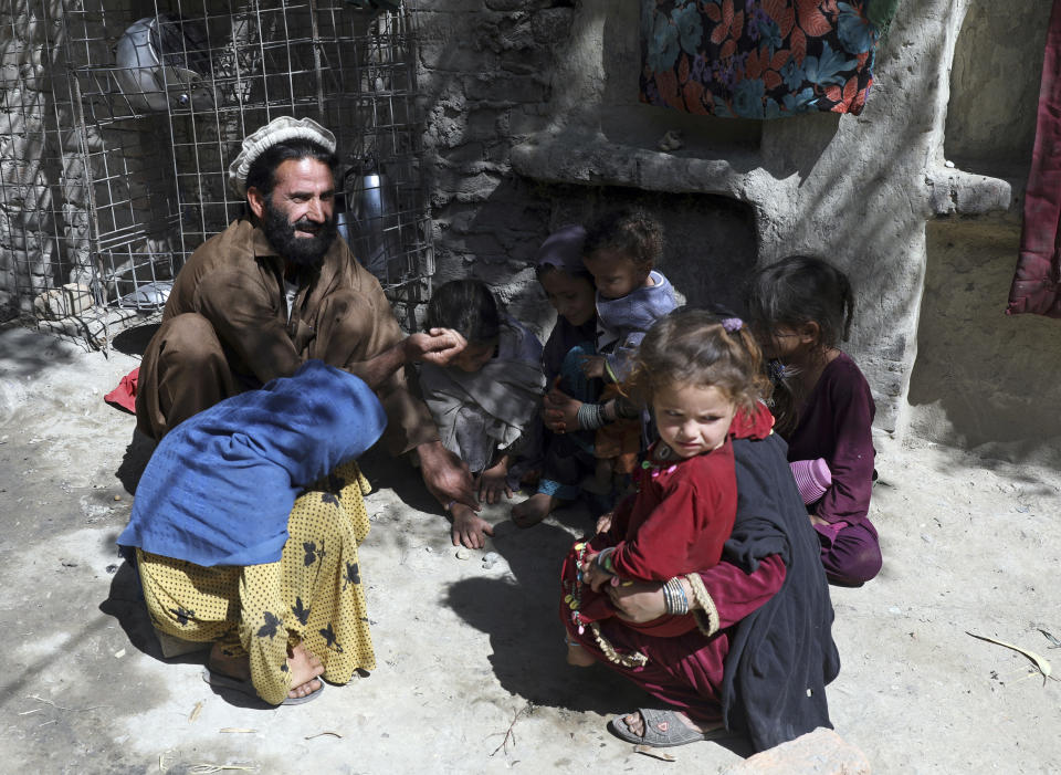 Internally displaced tribal leader Dawlat Khan plays with children and nephews in a house provided to him by relatives on the outskirts of Jalalabad, Afghanistan, Wednesday, April 21, 2021. Khan fled his village of Pananzai with his six brothers and their families at the height of the battles against the Islamic State terror network. They're not rushing home, even though the family of 63 people is crammed into nine small rooms. (AP Photo/Rahmat Gul)